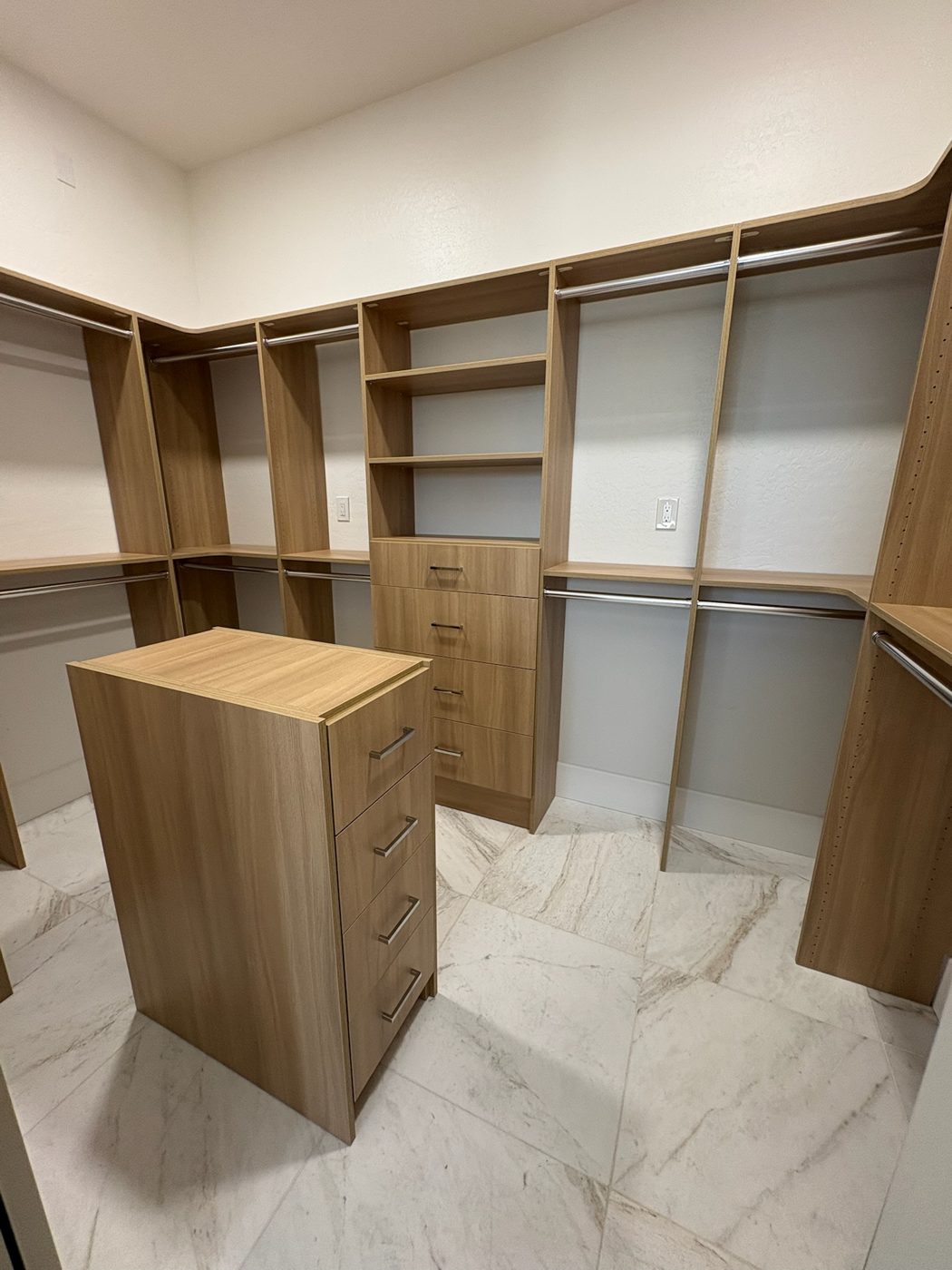 Oak walk-in closet with island on marble floor